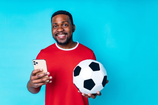 Latin,hispanic,man,with,phone,and,football,ball,in,studio