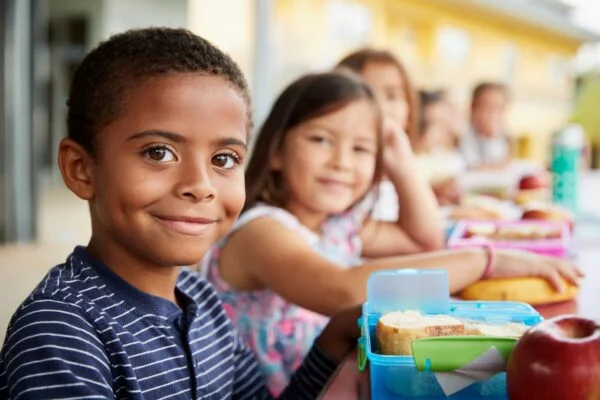 Young,boy,and,girl,at,school,lunch,table,smiling,to