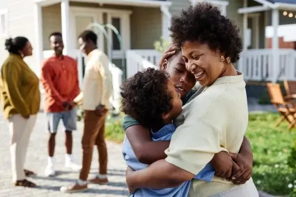 Portrait,of,smiling,black,woman,embracing,two,sons,at,family